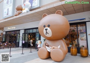 A woman posing in front of a teddy bear in a store.