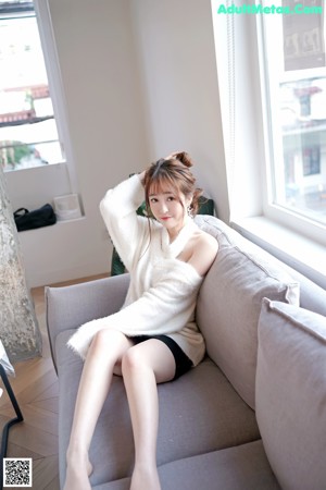 A woman in a white dress sitting on a bed.