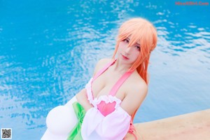 A woman in a pink bathing suit sitting on the edge of a pool.