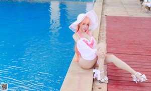 A woman in a pink bikini sitting by a swimming pool.