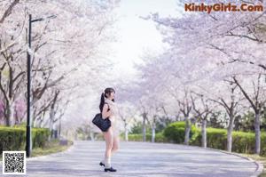 A woman in a white lingerie standing in front of a tree.