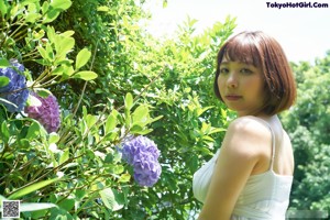 A woman in a white dress crouching in the grass.
