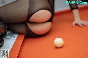 A woman in a fishnet bodysuit is playing pool.