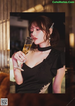 A woman in a black dress sitting on a couch.