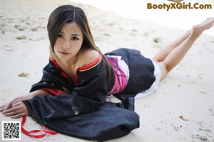 A woman in a black and red kimono sitting on a rock.
