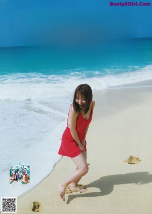 A woman in a blue bikini sitting on a beach.