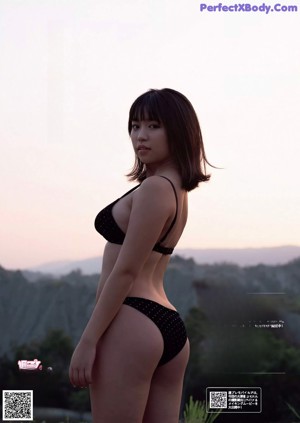 A woman in a bikini standing on a wooden structure.