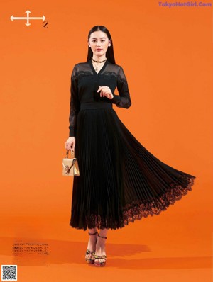 A woman in a black suit and a black bag.