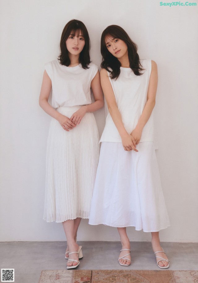 Two women standing next to each other in white dresses.