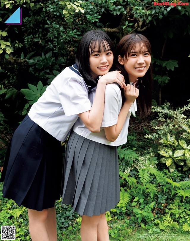 Two young women in school uniforms posing for a picture.