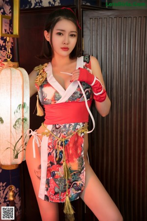 A woman in a red and white dress holding a fan.