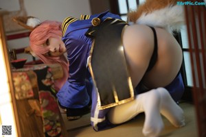 A woman with pink hair is sitting on the floor.