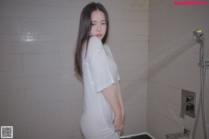 A woman in a white dress standing in a bathtub filled with foam.