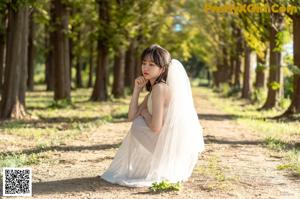 A woman in a white dress standing in a park.