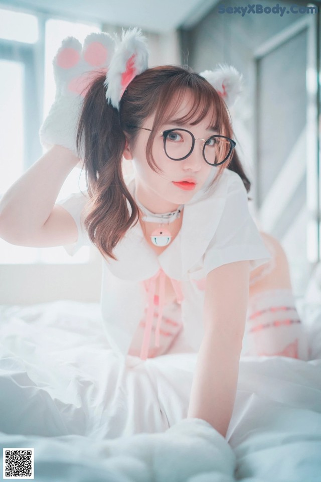 A woman in a white shirt and bunny ears laying on a bed.
