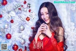 A woman sitting on the floor in front of a pink Christmas tree.