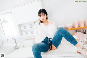 A woman standing in a kitchen next to a sink.
