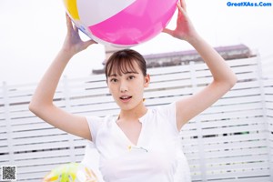 A woman in a bikini holding a beach ball over her head.