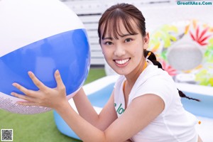 A young woman sitting on the ground with her hands on her face.
