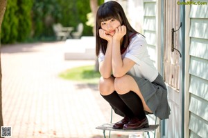 A woman in a school uniform pointing at something.
