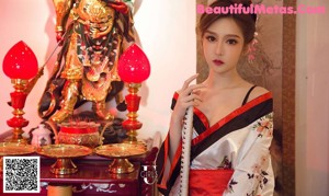 A woman in a kimono sitting on a couch holding a sword.