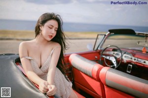 A woman sitting in the back seat of a red car.