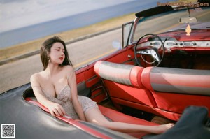 A woman sitting in the back seat of a red car.