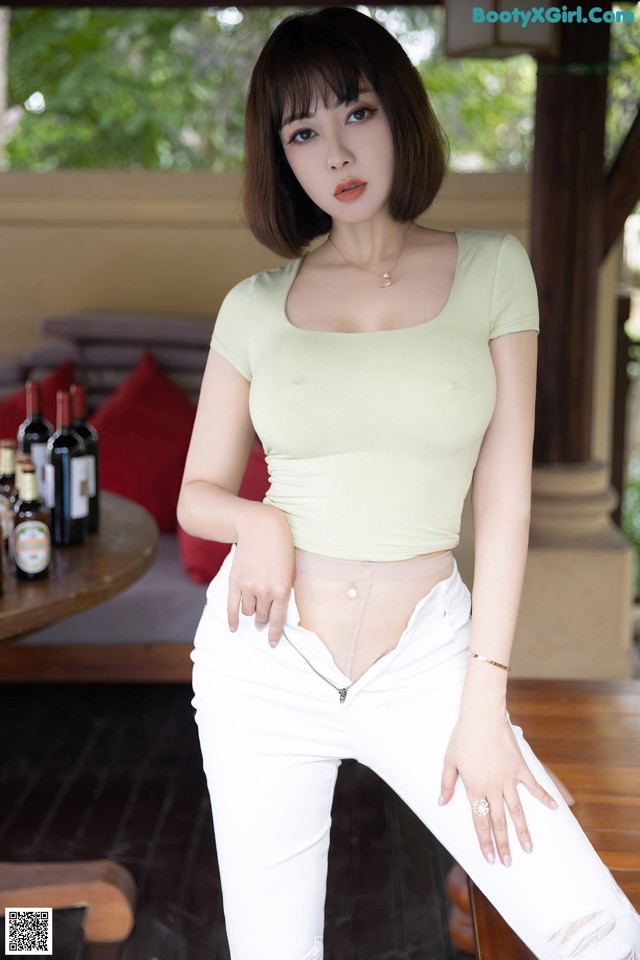 A woman in white jeans and a green top posing for a picture.