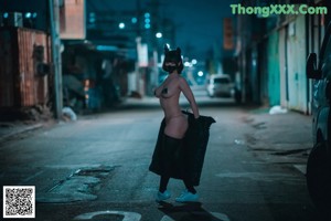 A woman in a cat mask is sitting on the street.