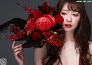 A woman holding a bouquet of red flowers in her hand.