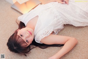 A woman in a white dress sitting on the floor.