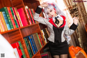 A woman in a red and white outfit is standing in front of a bookshelf.