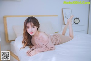 A woman sitting on a blanket holding a teddy bear.