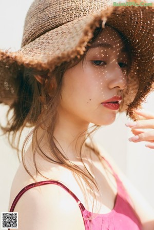 A woman with long brown hair wearing a white tank top.