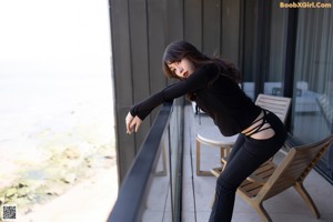 A woman sitting on a white couch wearing black pants and heels.