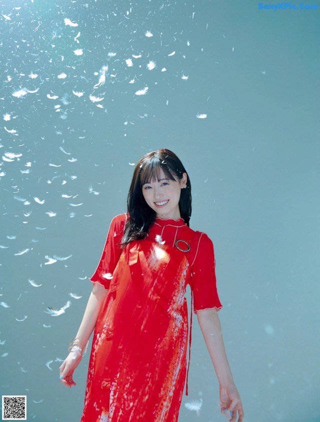 A woman in a red dress standing in front of a blue background.