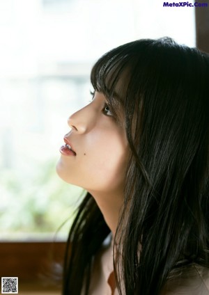 A young woman in a yellow sweater is smiling at the camera.