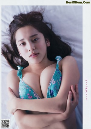 A woman laying on a bed in a blue bikini.