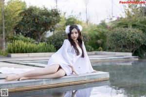 A woman in a white dress sitting in a bathtub.