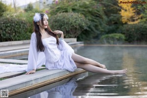 A woman in a white dress sitting in a pool of water.