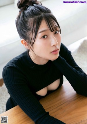 A woman in a black sweater and black panties sitting on a white couch.