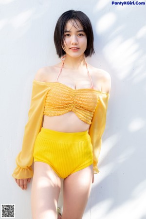 A woman in a yellow bikini sitting on a wicker chair.